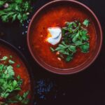 Pomidorų sriuba, kuri šildo ir stiprina organizmą: atraskite du netikėtus ingredientus Karšta pomidorų sriuba su pupelėmis ir mielėmis dubenyje su prieskoniais ant stalo.